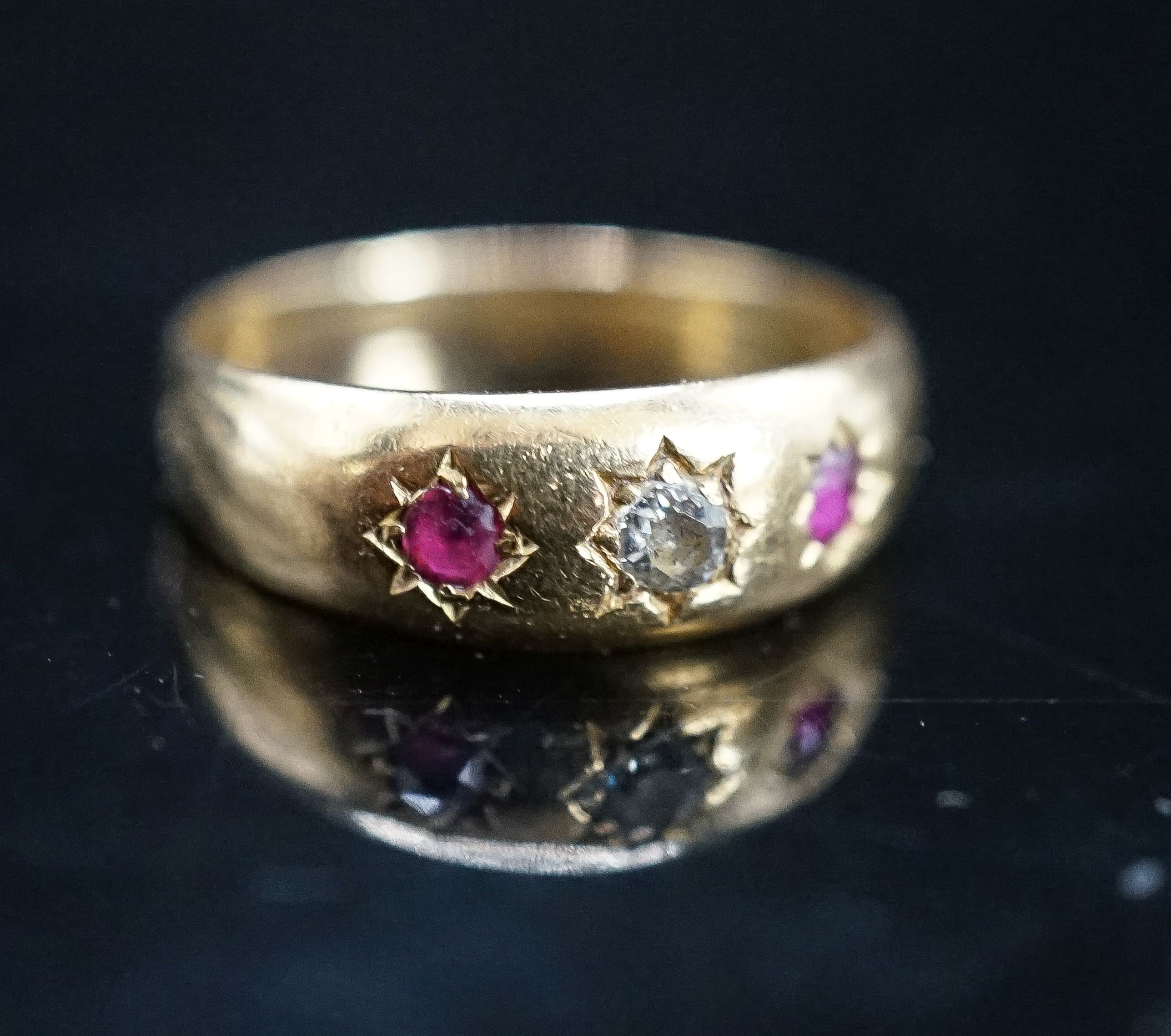 An early 20th century yellow metal and gypsy set ruby and diamond set three stone ring, size O, gross 3.9 grams.